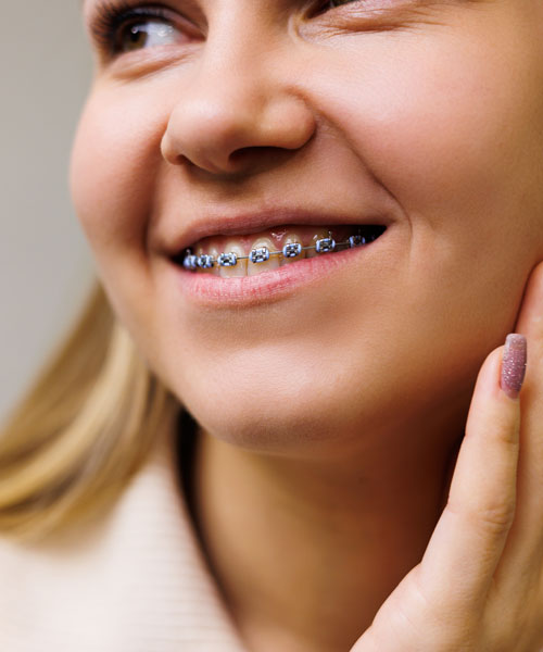 Una mujer sonriente con aparatos en los dientes espera en el gabinete dental a su médico. Gabinete en una moderna clínica dental
